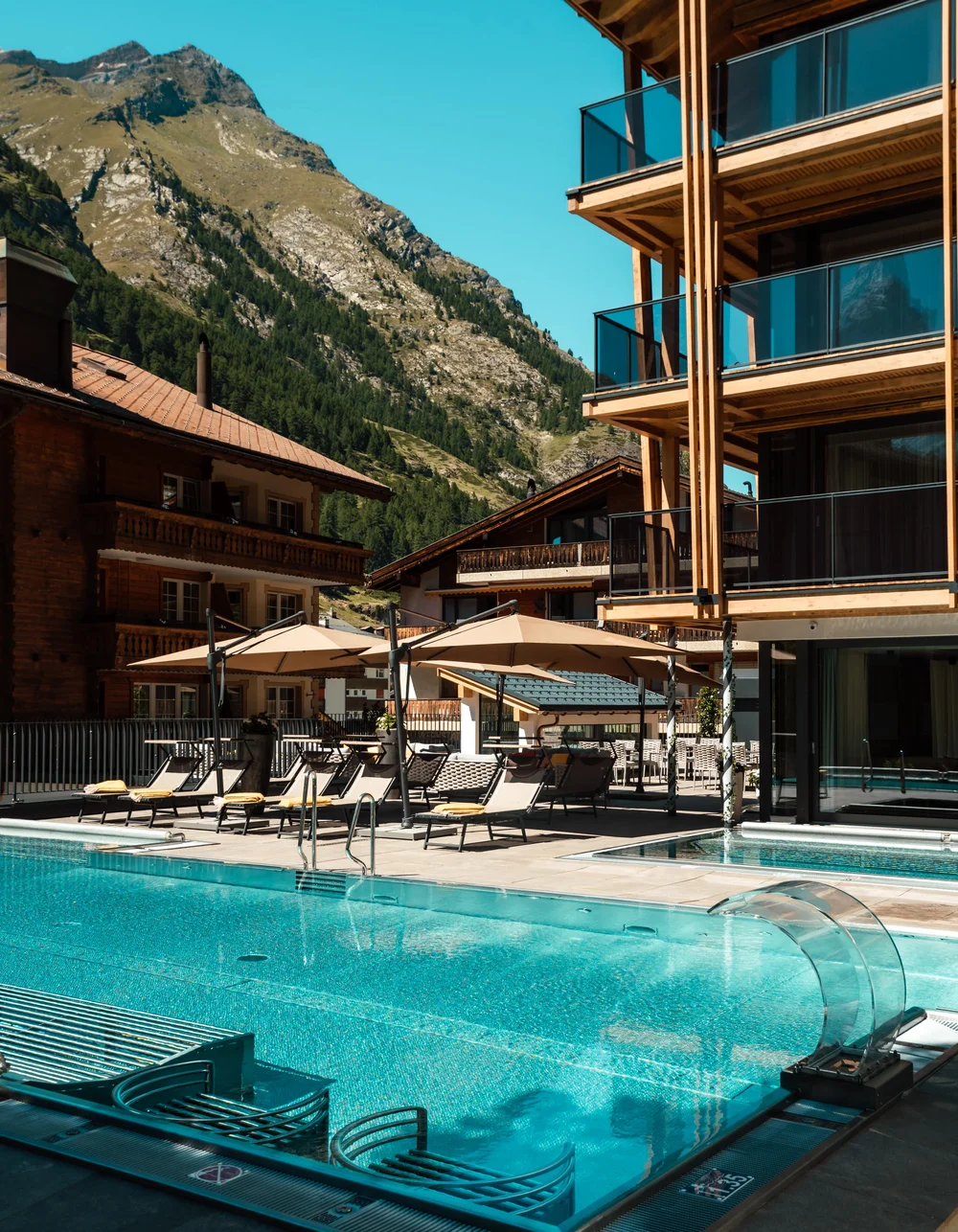 Wandern in Zermatt - Resort La Ginabelle Zermatt Infinitypool und Terrasse mit Bergen im Hintergrund im Sommer.