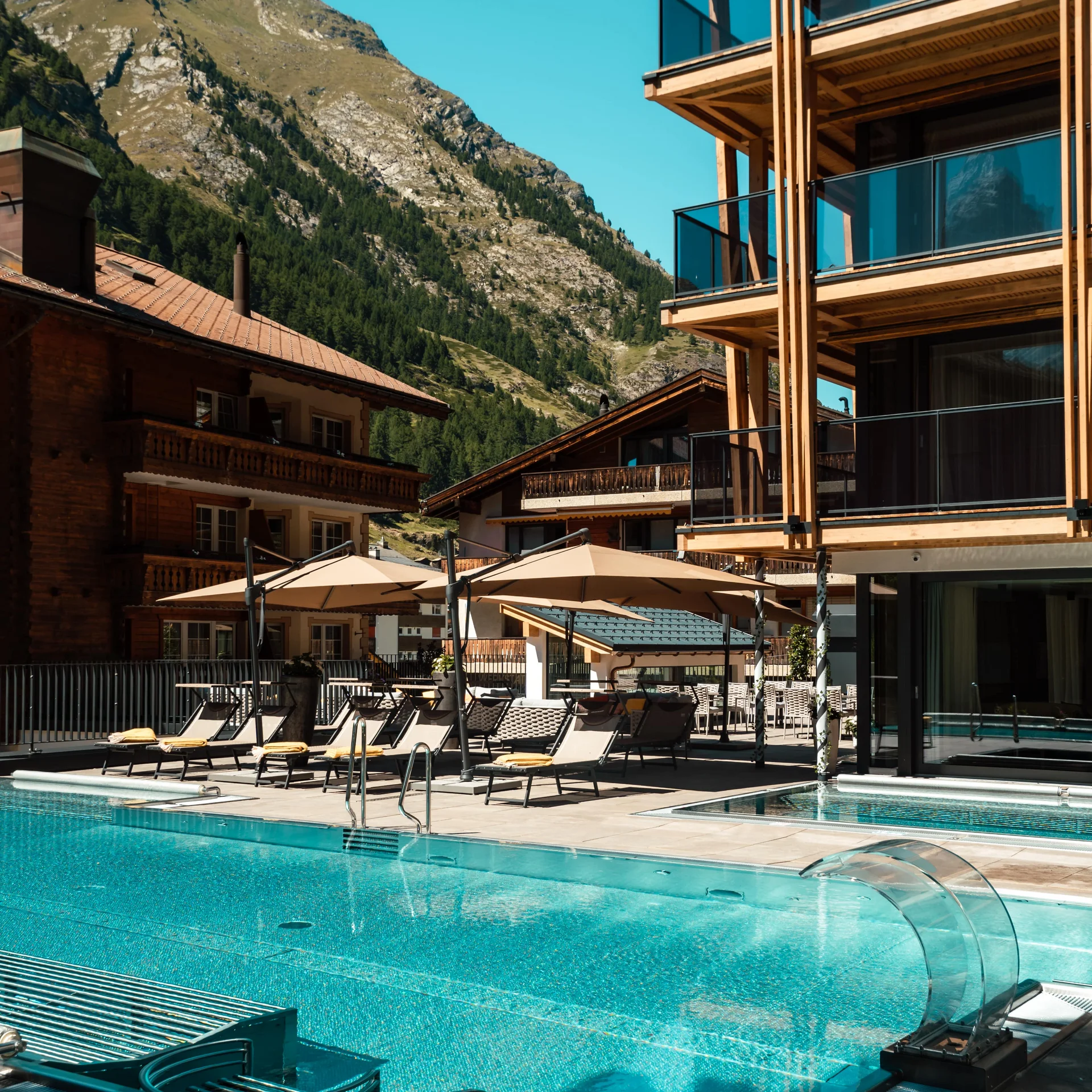 Infinitypool und Terrasse mit Bergen im Hintergrund im Sommer.