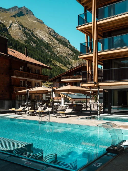 Infinitypool und Terrasse mit Bergen im Hintergrund im Sommer.