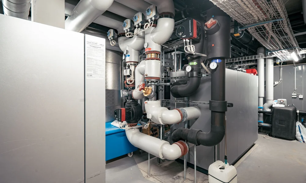 Our energy - Resort La Ginabelle Zermatt Geothermal heat pump with pipes and valves in a technical room.