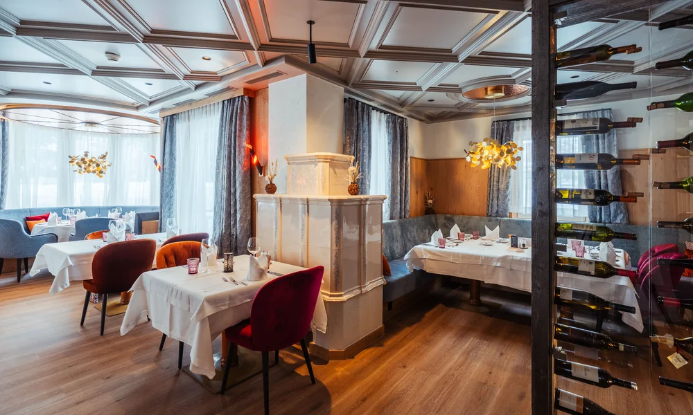 Restaurant La Ginabelle - Resort La Ginabelle Zermatt Modernes Restaurant mit traditionellem Kacheloffen und Weinshowstück.