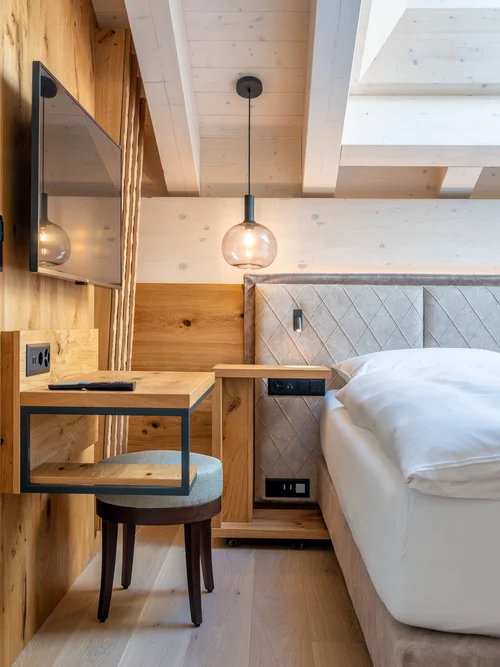 Modern hotel room area with wooden furniture, bed, and wall-mounted TV