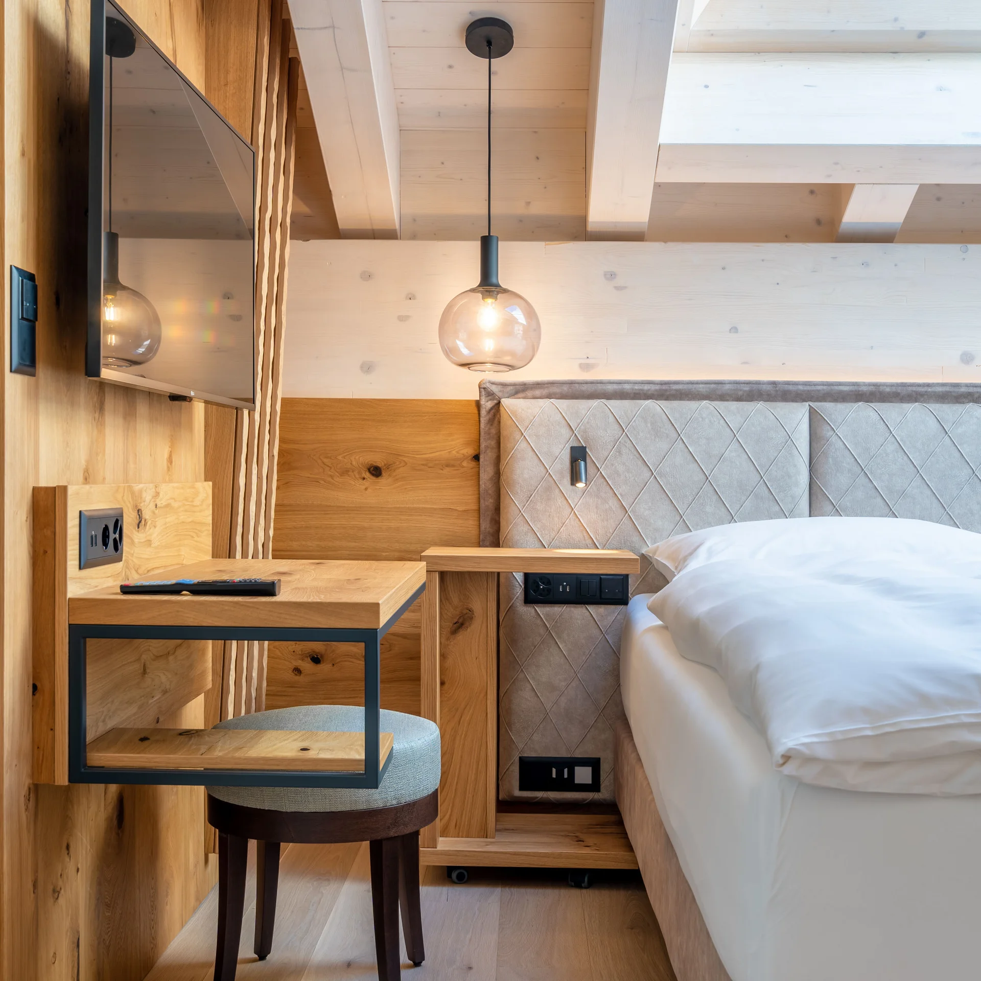 Moderner Hotelzimmerbereich mit Holzmöbeln, Bett und TV an der Wand