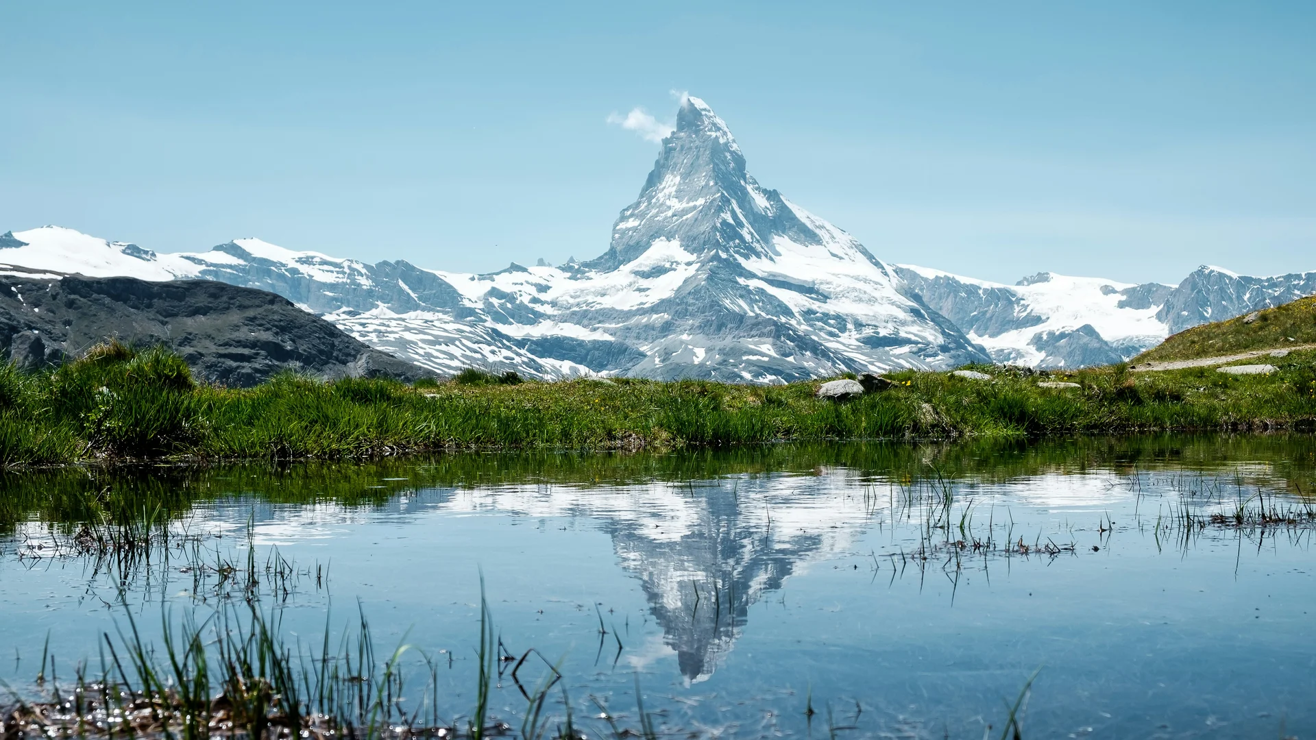 Klettern & Bergsteigen Matterhorn mit Schnee und Spiegelung im Wasser auf grüner Wiese