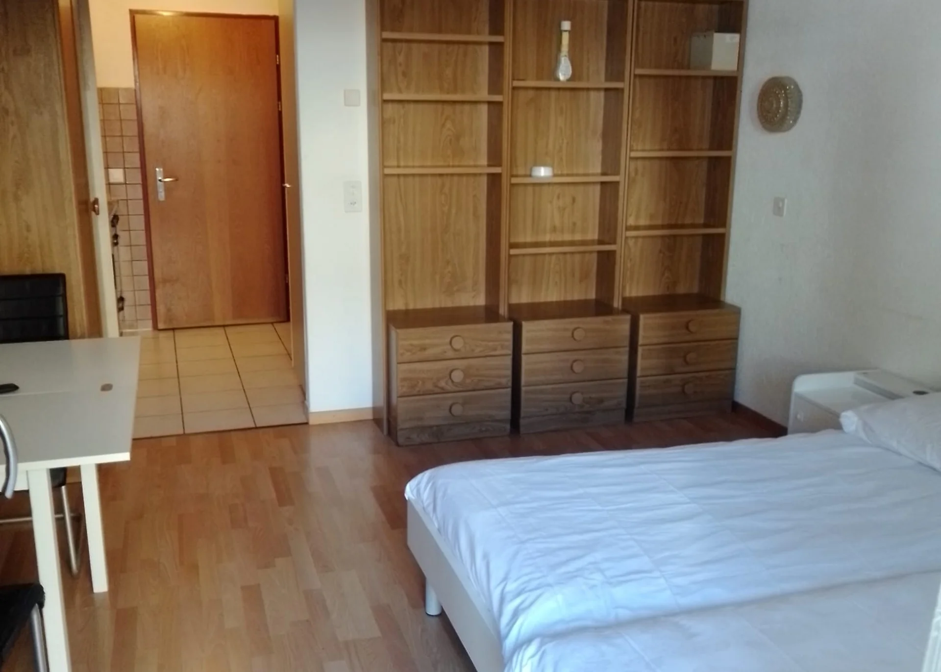 Studio eingerichtet mit Schrank, Tisch und Bett.