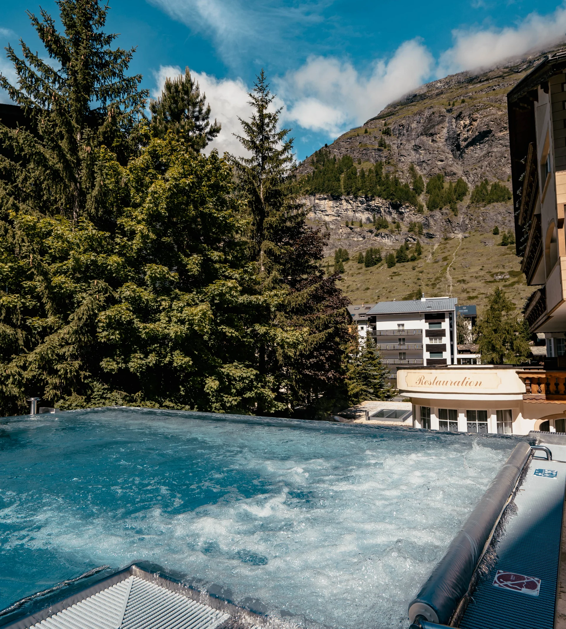 Why Choose La Ginabelle Infinity pool with massage jets and view of the mountains in summer.