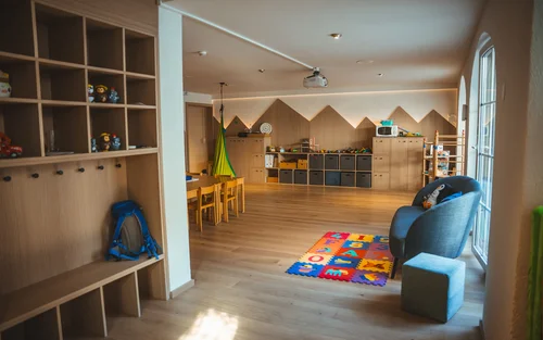 Resort de Bien-Être à Zermatt - Resort La Ginabelle Zermatt Salle de jeux pour enfants avec étagères en bois, jouets et tapis coloré
