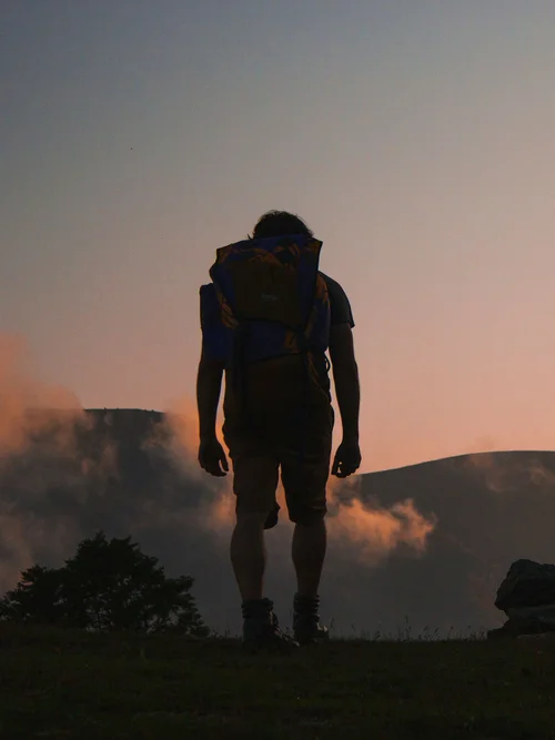 Aktivurlaub in den Bergen - Resort La Ginabelle Zermatt Wanderer mit Rucksack vor Berg im Sonnenuntergang
